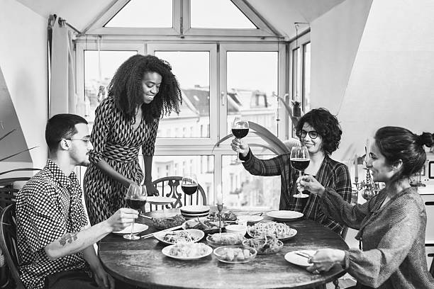 istock four people around wooden lunch table clinking wine glasses 2212199275