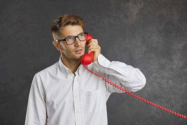 istock Studio portrait of serious focused man talking on landline phone and looking up thoughtfully. 2212204792