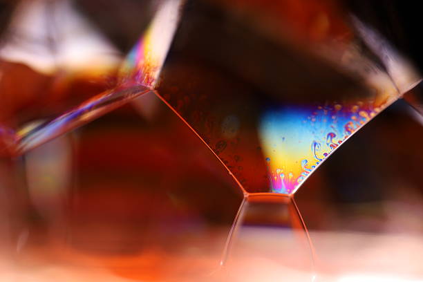 istock Bright rainbow reflection of liquid on dark red background 2212211723