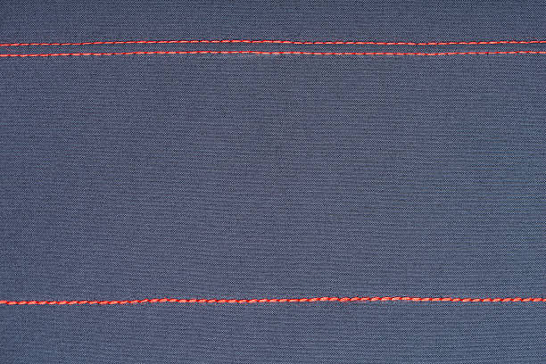 Close-up of fabric texture with red stitch on lilac cotton, textile surface for sewing, upholstery, and craft design.