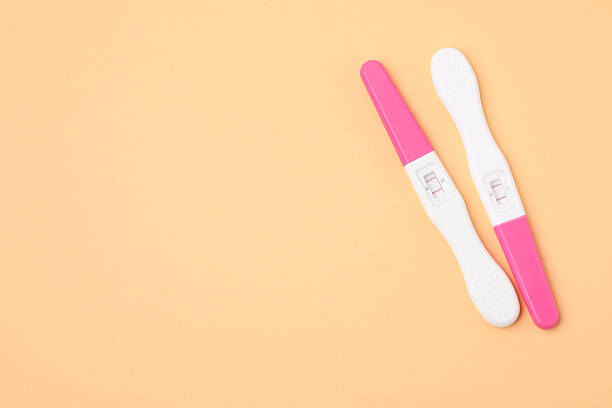 Close-up of female hand holding a pregnancy test strip indoors, symbolizing personal health and decisions.