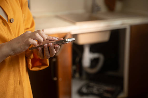 Woman using app to find plumber for sink repair stock photo