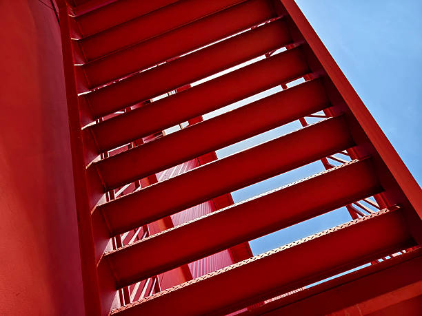 A set of stairs ascending a large red wall.