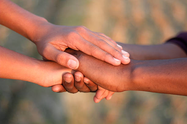 Young caucasian female volunteer holding hand of african child's hand in Ethiopian village.