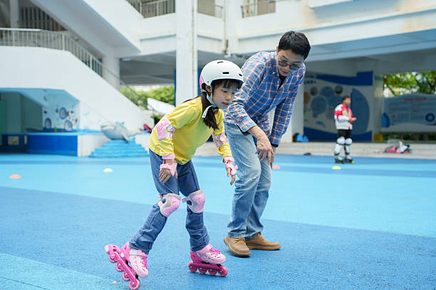 Asian man accompanies his daughter in roller skating