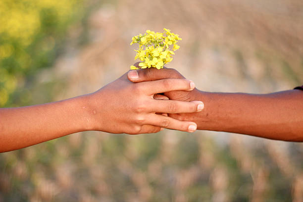 A man holding some mustard flowers in his two hand and background blur