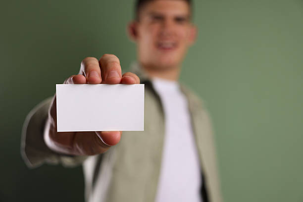 istock Man holding blank business card on green background, selective focus. Mockup for design 2212215099