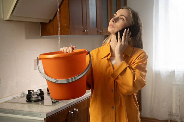istock Woman calling for help holding bucket under water leak in kitchen 2212215607