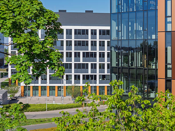 istock Modern office buildings surrounded by greenery in a bright urban setting under clear blue sky 2212215683