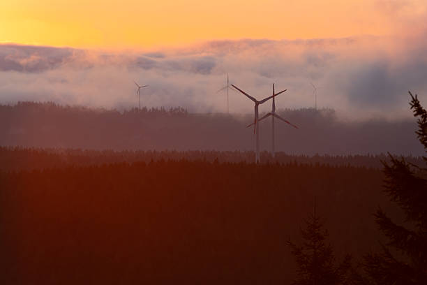 a windmills generators in the mountains covered with clouds at sunrise time