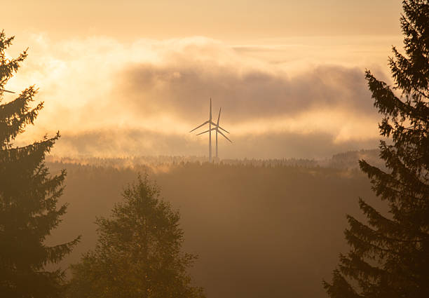 a windmills generators in the mountains covered with clouds at sunrise time
