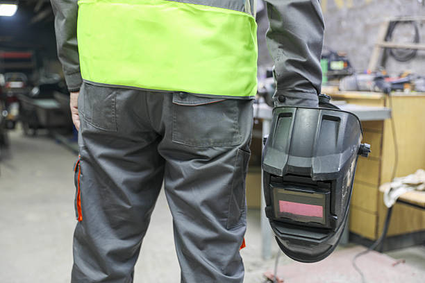 Human hands hold welding equipment at a job site.