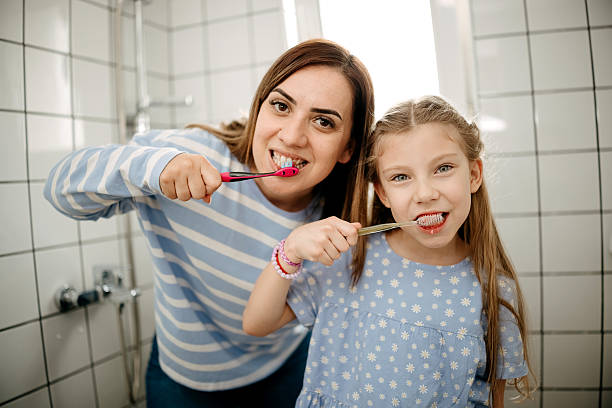 istock Mother and daughter brushing teeth 2212218213