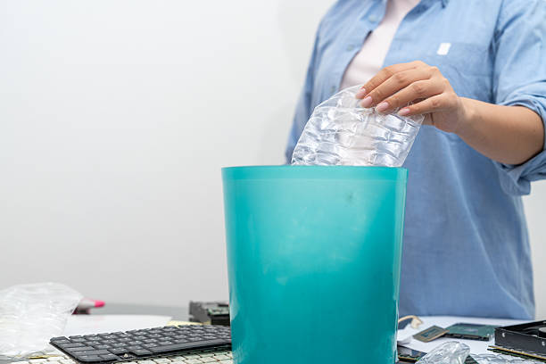 Close-up, Asian woman separating general waste, plastic bottles, paper and e-waste or electronic waste for recycling.