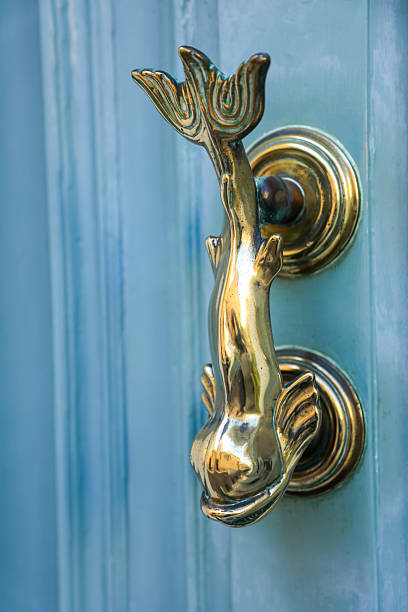 An antique bronze door handle on a blue door that has been passed down through generations.