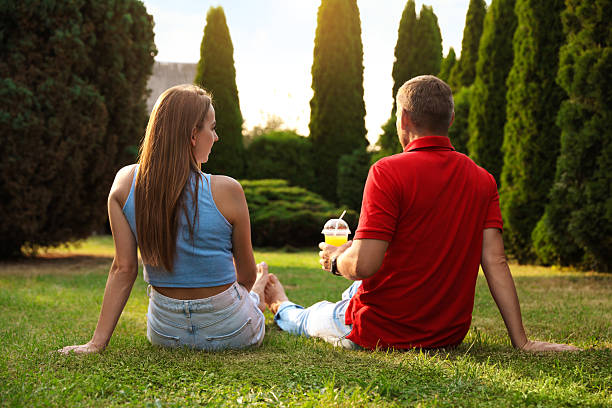 Personal perspective of young couple in 20s and 30s sitting outdoors in backyard and enjoying weekend breakfast.