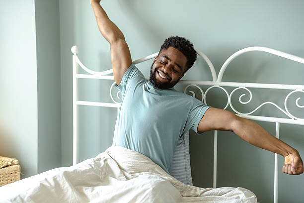 istock Man stretching in bed during morning in a cozy bedroom setting 2212228234