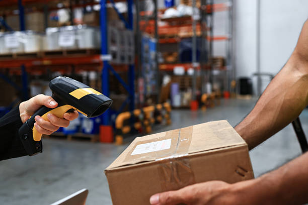 istock employee scanning barcodes on packages, checking cardboard boxes in warehouse with tablet. Person doing merchandise inventory or logistics, preparing distribution. Handheld shot. 2212228518