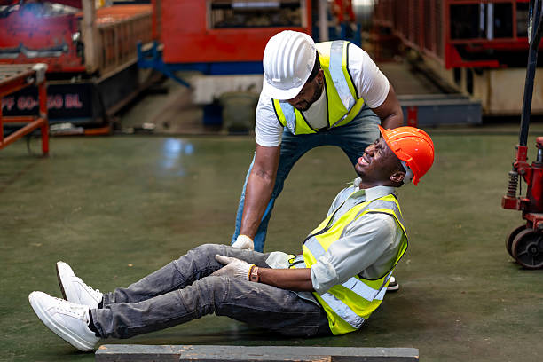 istock African American factory worker having accident while working in manufacturing site while his colleague is helping  for safety workplace and emergency 2212231895