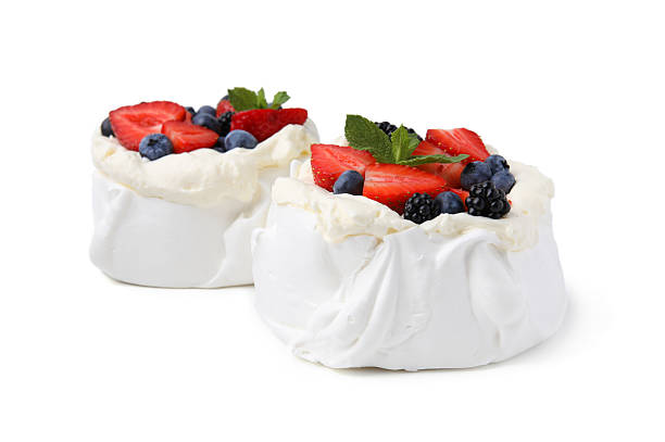 istock Pavlova cake (meringue dessert) with whipped cream, fresh berries and mint isolated on white 2212237462