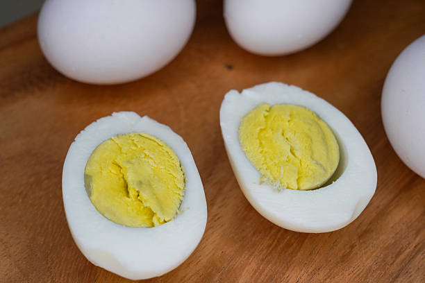 istock Different cooking time and readiness stages of boiled chicken eggs on wooden table, flat lay. Selective focus on eggs. 2212240621