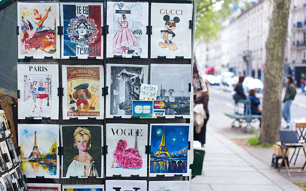 Paris, France: A retail display of vintage posters and Vogue magazine covers at an outdoor antiquarian bookseller (bouquiniste) on the banks of the Seine on a sunny day.