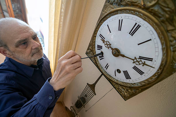 istock Man Adjusting a Vintage Wall Clock with Intricate Design 2212243612