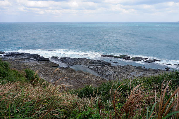 istock Rocky coastline with tide pools and waves crashing on the shore under a cloudy sky. 2212245537