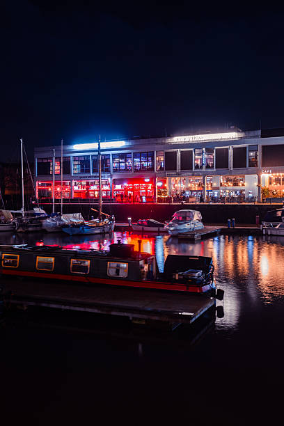 Illuminated buildings and boats create a vibrant scene at night in bristol's harbor