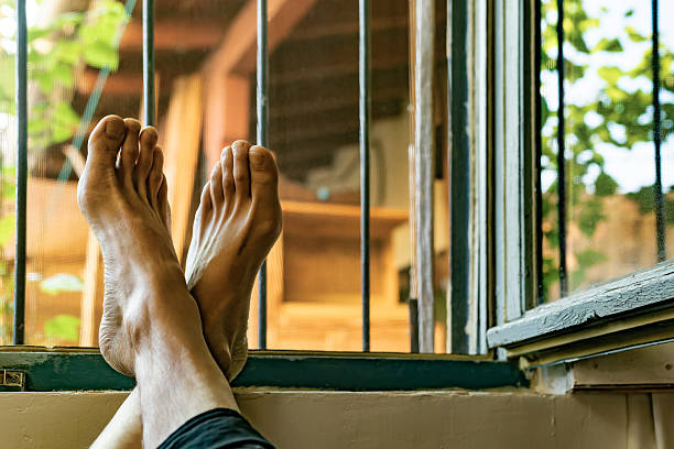 Madrid. Spain. Resting comfortably with feet propped up on an open window sill, enjoying the warmth of a sunny day and taking in the peaceful view of a backyard oasis