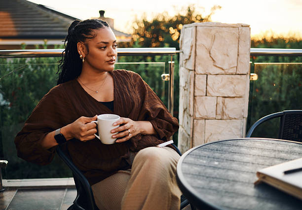 istock Thoughtful Woman Enjoying Coffee on a Balcony at Sunset 2212253496