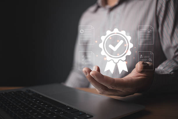 istock A person holds a glowing quality control badge hologram featuring a checkmark and surrounding digital document icons, symbolizing certification, standards, and reliable assurance in modern processes. 2212263411
