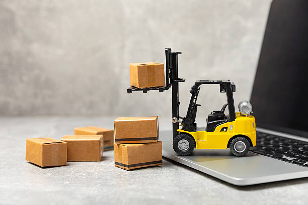 istock Yellow forklift on bright textured background. Logistics concept. Logistics and supply chain management for online shopping concept. Delivery of goods or products to the store worldwide. Cardboard box 2212263950