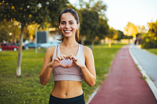 istock Woman Smiling Outdoors While Making a Hand Heart Symbol 2212264947