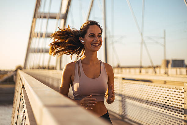 istock Smiling Woman Jogging on a Bridge at Sunset in Activewear 2212265029