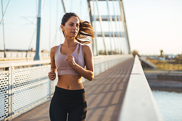 istock Young Woman Jogging on a Bridge During a Vibrant Sunny Day 2212265068