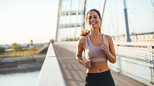istock Woman Jogging on Bridge with a Bright Smile During Sunset 2212265070