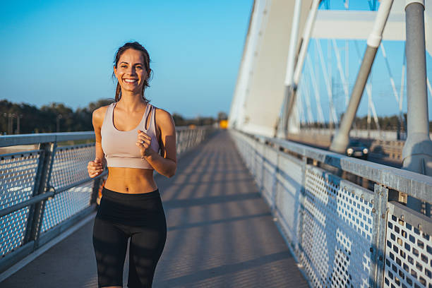 istock Smiling Woman Jogging on Bridge During a Sunny Day 2212265105