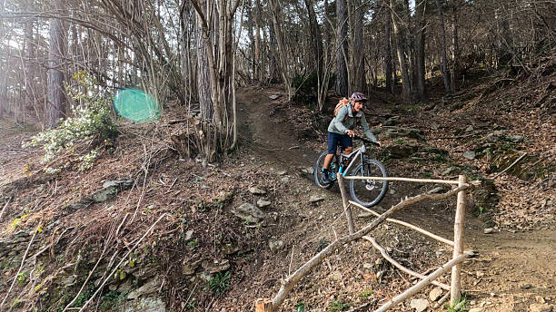 istock Mature man rides e-mountain bike down narrow trail in forest 2212265452