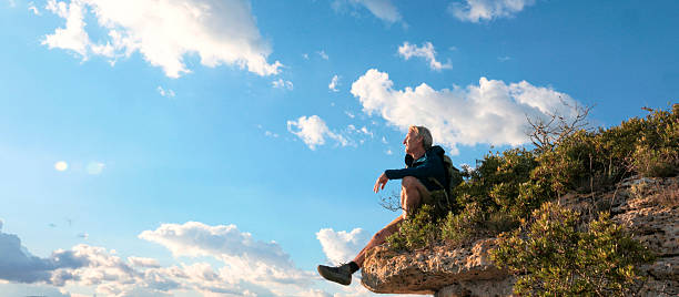 Hiker on edge of mountain above valley and mountain ranges, Liguria