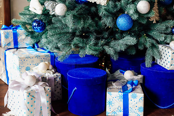 istock Festive blue and white gift boxes under a Christmas tree decorated with ornaments 2212265840