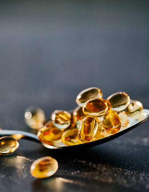 istock Golden Softgel Capsules on Silver Spoon 2212266195