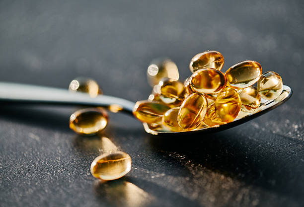 Golden Softgel Capsules on Silver Spoon