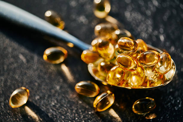 istock Golden Softgel Capsules on Silver Spoon 2212266202