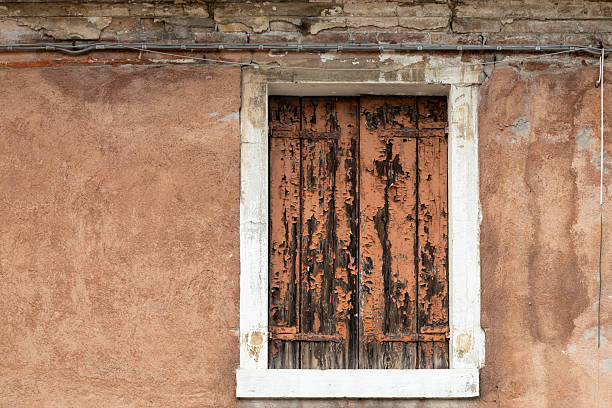 istock Old window with heavily weathered wooden shutters and rustic wall texture 2212271675