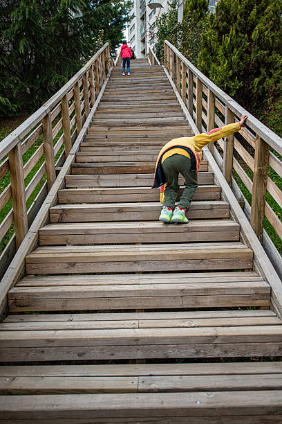 Side view of a small baby struggling up the steps, small baby climbing the stone steps in the park.