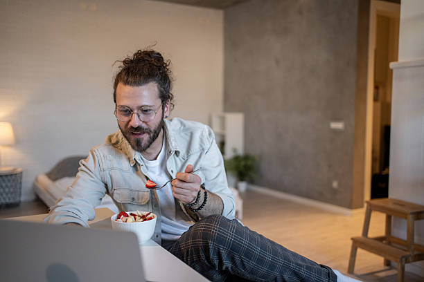 istock Young man working remotely and eating a fruit salad 2212274051