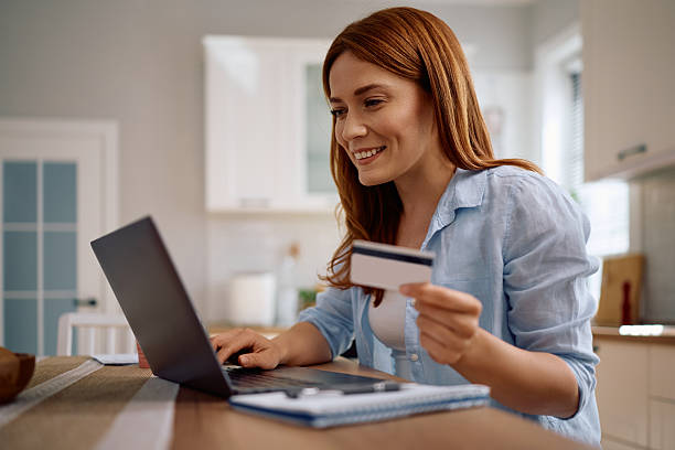istock Happy woman using credit card while paying online at home. 2212274355