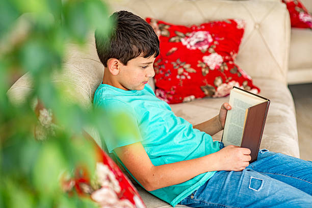 istock Boy reading a book in the living room 2212280981