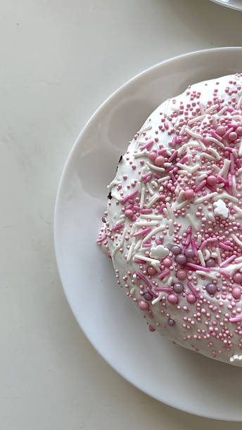 Delicious round cake topped with pink sprinkles and icing on a white plate showcasing a delightful dessert perfect for celebrations and special occasions, sweet treat concept
